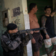 “A police officer takes position near residents during an operation against drug traffickers at the ‘pacified’ Jacarezinho slum in Rio de Janeiro, Brazil.”